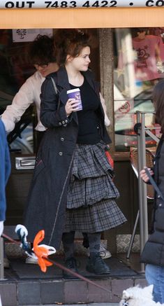 a woman walking her dog on a leash in front of a coffee shop while holding a drink