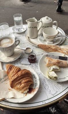 a table topped with plates and cups filled with breakfast foods on top of each other