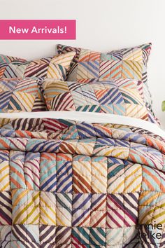 a bed with colorful quilts on it and the words new arrivals written in pink