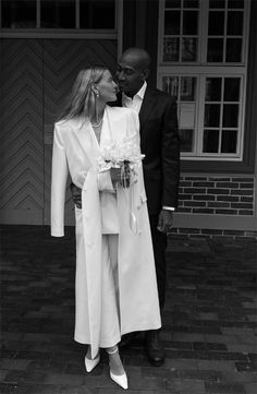 a man and woman standing next to each other in front of a building, kissing