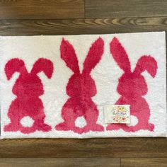 the rug has three rabbits on it and one is pink with white trim, while the other two are red