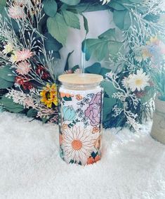 a colorful cup sitting on top of a white rug next to flowers and greenery