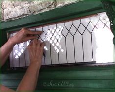 a person is painting the glass in front of a window with white paint and green trim