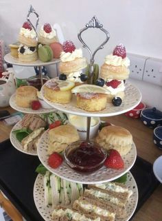 three tiered trays filled with cakes and pastries on top of a table