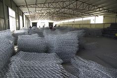 several stacks of galvanized wire in an industrial building with people walking around them