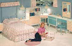 a woman sitting on the floor in a bedroom with blue walls and pink furniture,