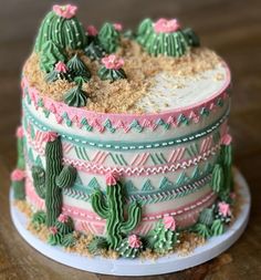 a cake decorated with green, pink and white frosting on top of a wooden table