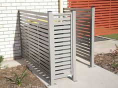 a metal gate sitting on top of a sidewalk next to a brick wall and grass