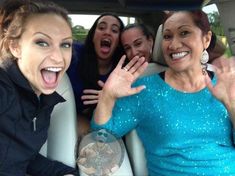 a group of women sitting in the back of a car with their mouths wide open