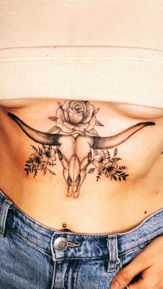 a woman's stomach with a cow skull and flowers on the side, in front of her belly