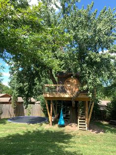 there is a tree house in the back yard with a blue trampoline on it