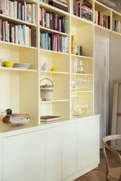 a room filled with lots of books and furniture next to a wall full of shelves