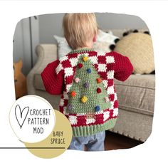 a small child wearing a crochet christmas sweater with a tree on it's back