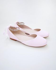 a pair of pink shoes with pearls on the toe and bow at the back, against a white background