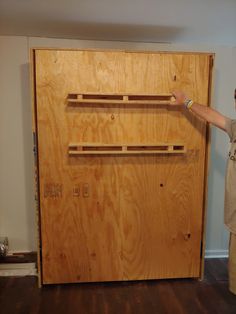 a man standing in front of a wooden wall with shelves on it's sides