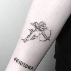 a small tattoo on the arm of a woman with an angel and name written in cursive font