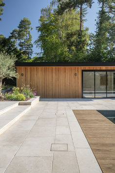 an outdoor area with a pool and wooden walls, surrounded by trees in the background