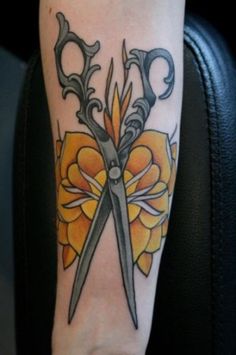 a tattoo with scissors and flowers on it