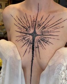 a cross tattoo on the back of a woman's upper body, with black ink sprinkles