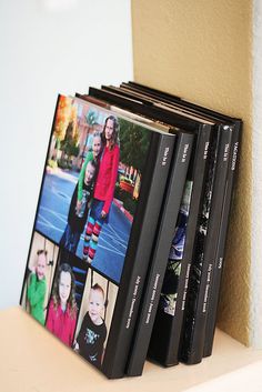 three books are stacked on top of each other in front of a wall with pictures