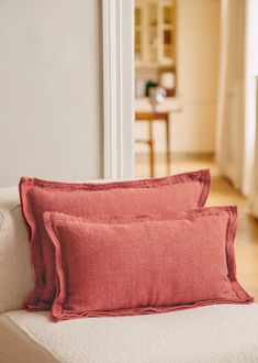 two red pillows sitting on top of a white couch