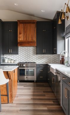 a kitchen with black cabinets and white counter tops, wood flooring and stainless steel appliances