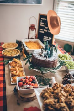 a table topped with lots of food and desserts next to a hat on top of it