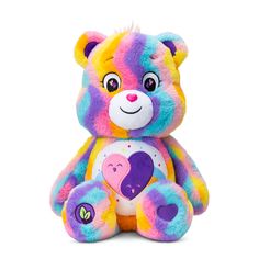 a multicolored teddy bear sitting on the ground with one eye open and two hearts painted on its chest