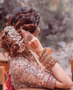 a woman sitting at a table with her hands on her face and hendi tattoos