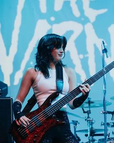 a woman holding a bass guitar on stage