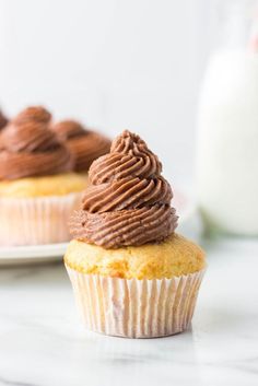 two cupcakes with chocolate frosting sitting on pink and white plates next to each other