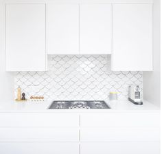 a kitchen with white cupboards and a stove top that has an oven in it