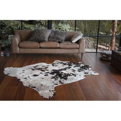 a living room with a brown couch and white cowhide rug on the wooden floor