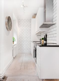 a kitchen with white walls and wooden floors