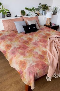 a bed with pink and orange bedspread, pillows and blankets on top of it