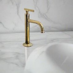 a gold faucet sitting on top of a white counter next to a sink