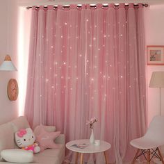 a living room with pink curtains and hello kitty decorations on the wall, white chairs and a round table