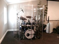 a drum set in a glass case next to an air conditioner and other musical equipment