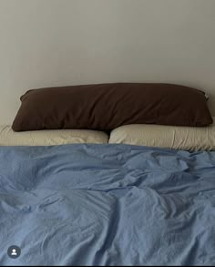 an unmade bed with two pillows on top of it and a blue comforter