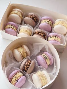 two boxes filled with assorted macaroons on top of a white table next to each other