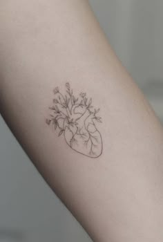 a small heart tattoo with flowers on the left side of the arm and behind it