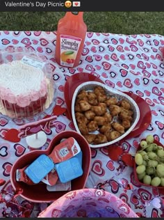 a table topped with lots of food on top of a pink and white cloth covered ground