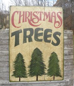 a wooden sign that says christmas trees on the side of a building with pine trees painted on it