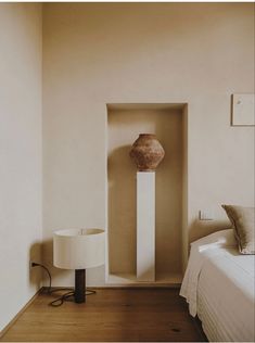 a bed sitting next to a lamp on top of a wooden floor