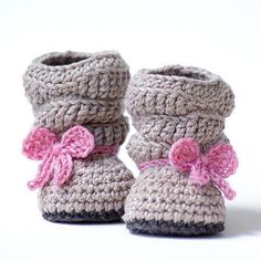 a pair of crocheted baby booties with pink bows on the front and bottom