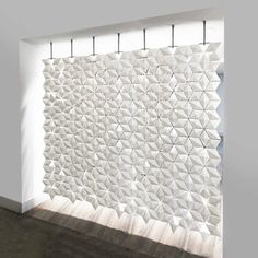 a room with a wall made out of white tiles and wooden flooring next to a window