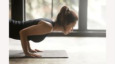 a woman doing push ups on a yoga mat