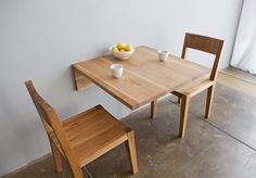 two wooden chairs sitting at a table with a bowl of fruit on it