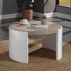 a coffee table with a book, potted plant and cup on it in a living room