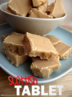 pieces of peanut butter fudge on a blue plate with a white bowl full of it